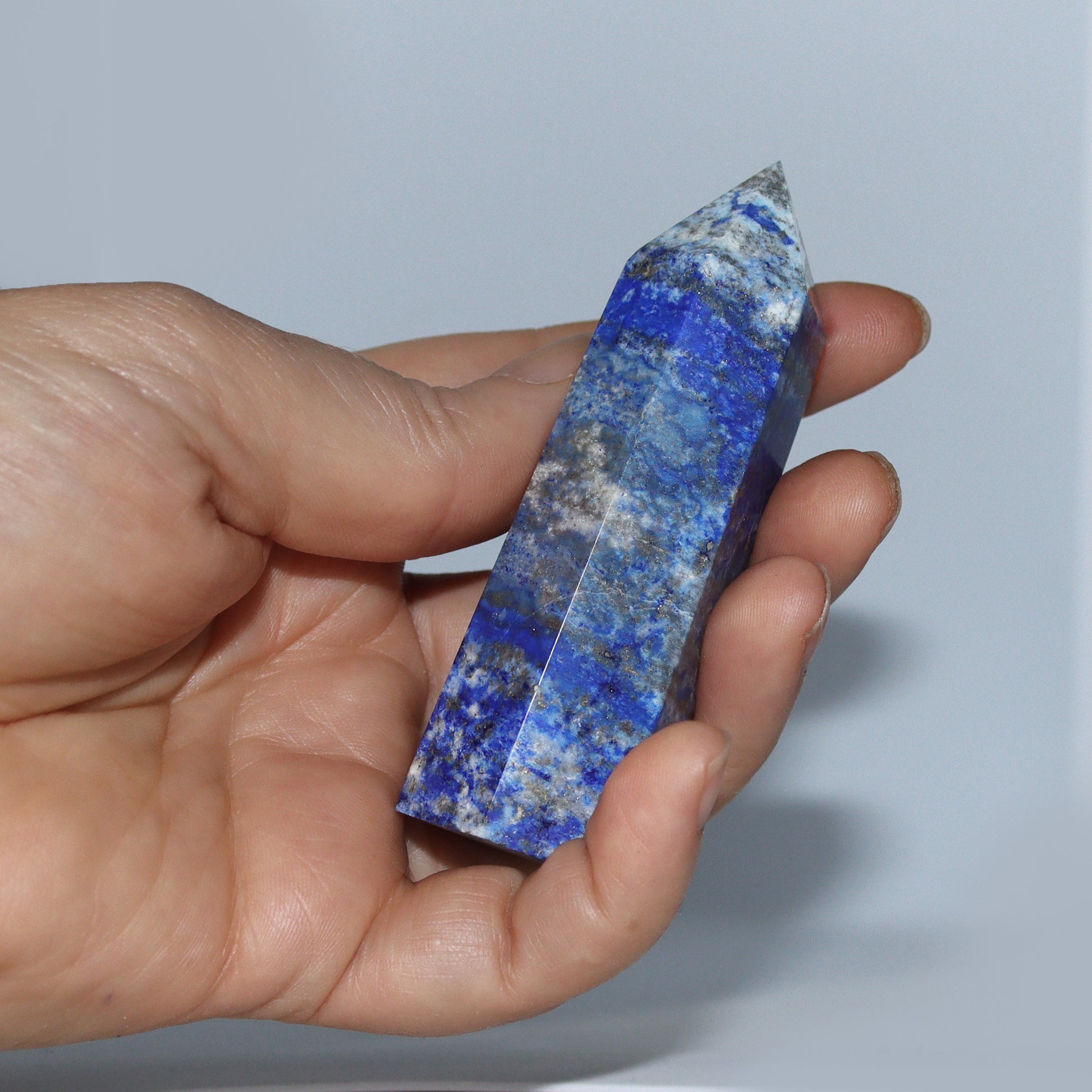 Blue Lapis Lazuli Crystal Hexagonal Tower / Obelisk shown in hand. Esoteric spiritual gifts from our New age Metaphysical store.